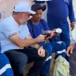 Alysson Bestene senta na calçada com trabalhadores durante acompanhamento de obras em Rio Branco