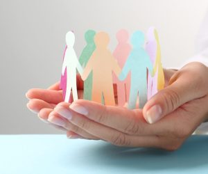 Woman holding paper human figures at table, closeup. Diversity and Inclusion concept